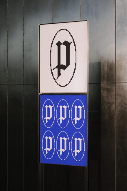 Stacked poster mockup with pixelated symbol on cream above repeated arch pattern