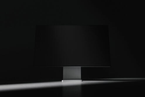 Dark minimalist monitor mockup centered on desk against black background