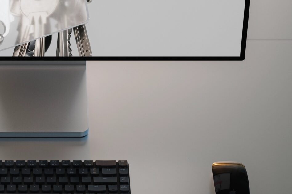 Desktop monitor angled down with mechanical keyboard in minimal workspace