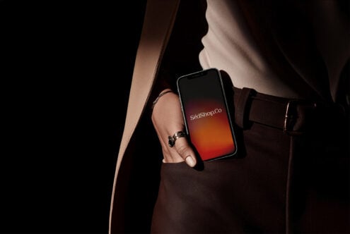 Woman in brown leather bag holding phone with red-orange gradient screen