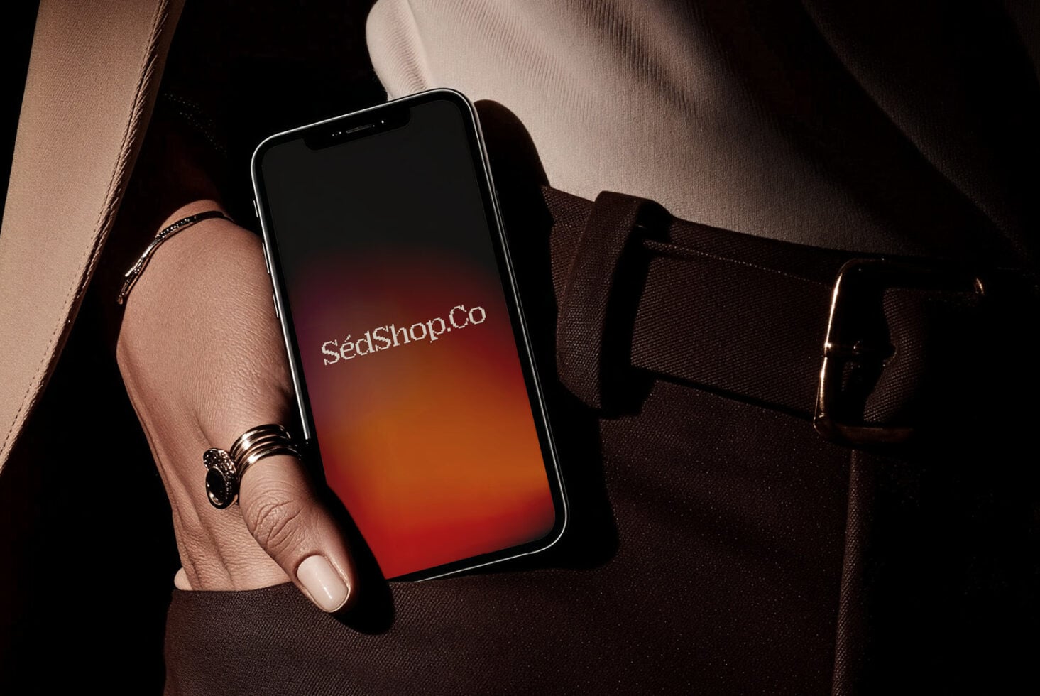 Woman in brown bag holding iPhone with warm gradient screen showing SédShop.Co text