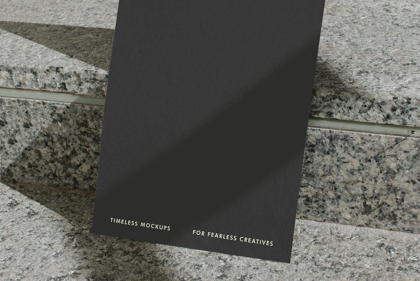 Dark card stood upright on layered stone showing lower portion with small text