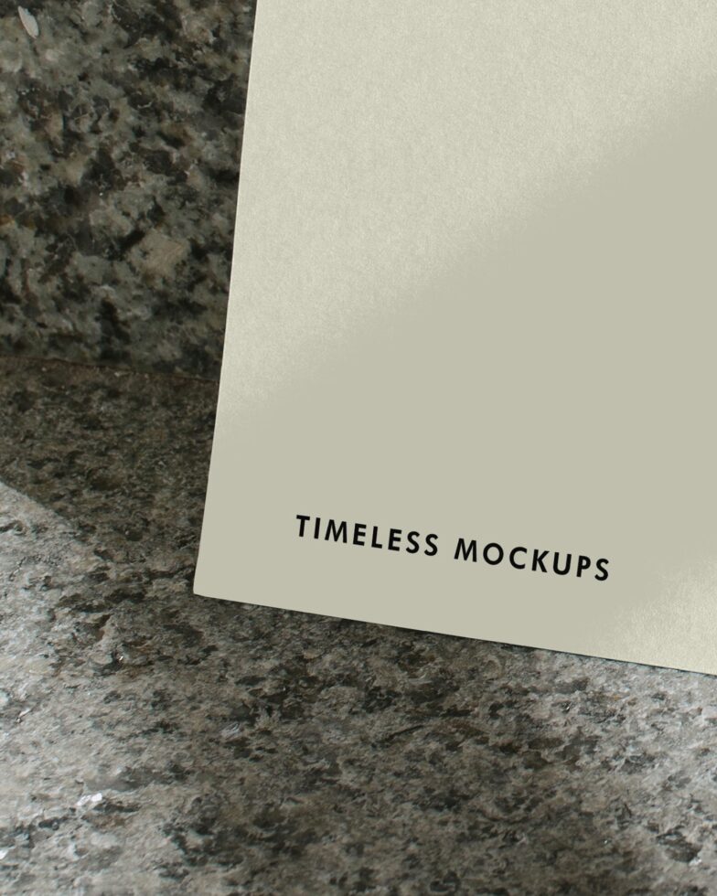 Cream colored card tilted on weathered stone showing Timeless Mockups text detail