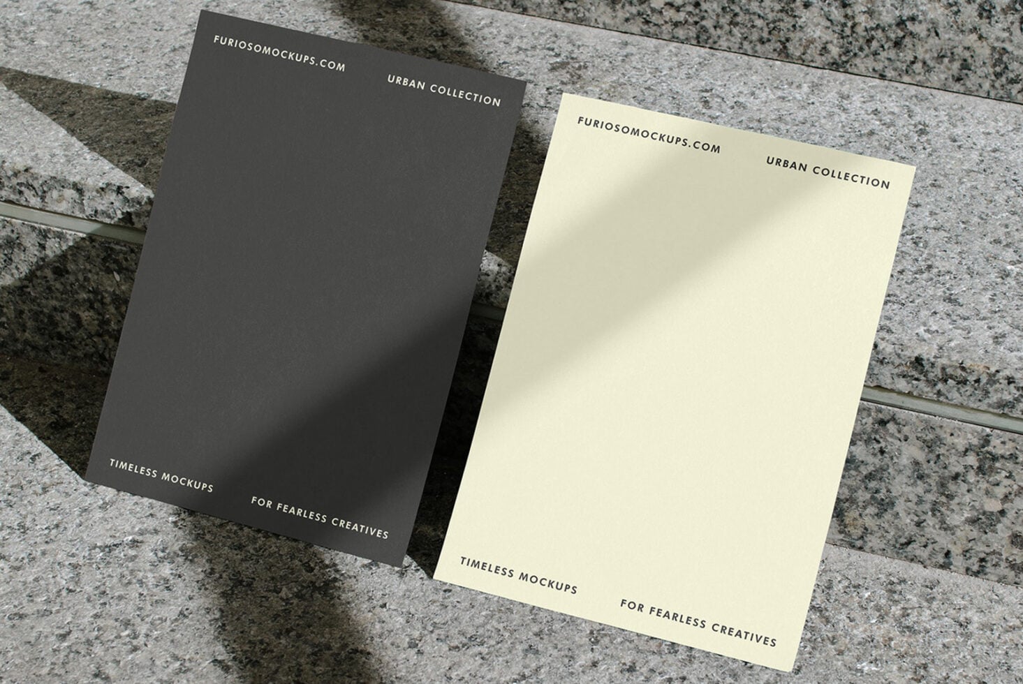 Dark gray plus cream colored cards angled on speckled stone background with shadows