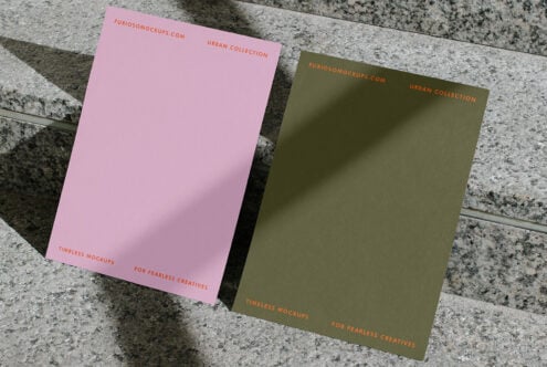 Pink, olive, plus cream colored cards fanned out on textured concrete surface