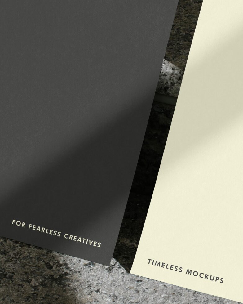 Dark grey card leaning against cream colored card on textured concrete background