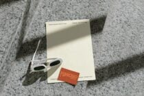 Cream letterhead with white sunglasses plus orange card on textured ground