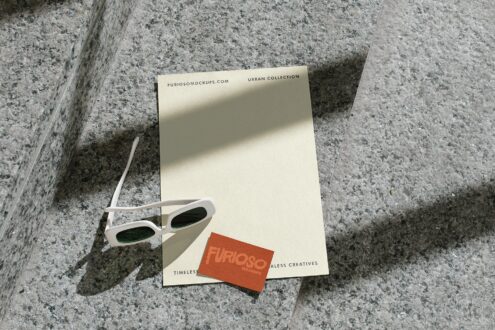 Cream letterhead with white sunglasses plus orange card on textured ground