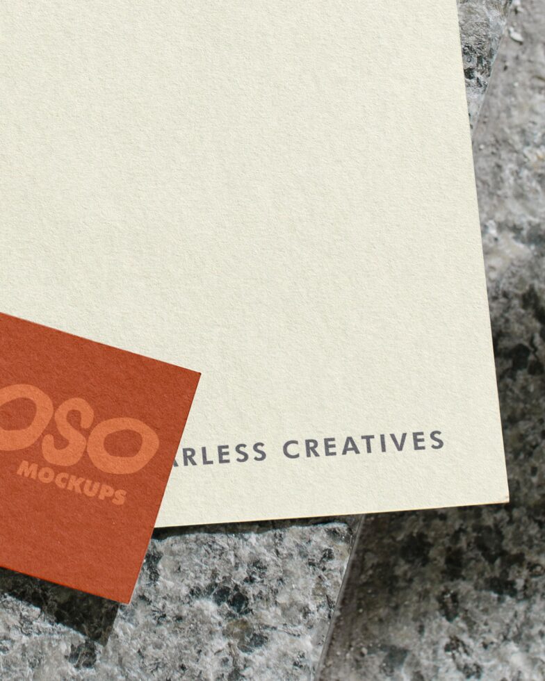 Red corner card detail overlapping cream letterhead on concrete surface