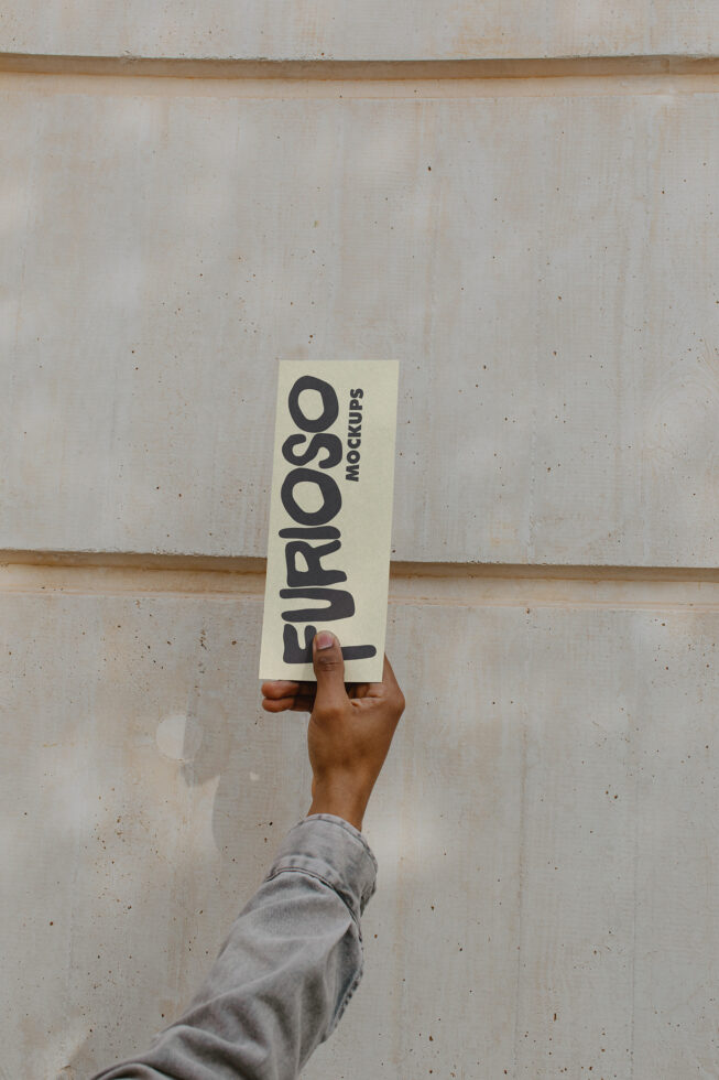 Light colored vertical card mockup in hand positioned against concrete