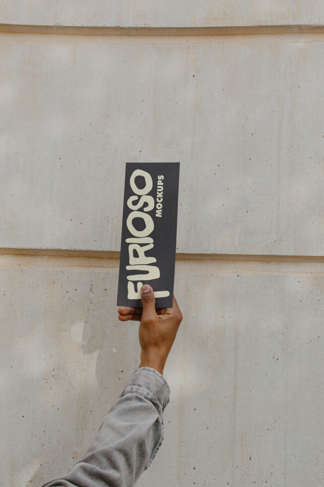 Dark vertical card mockup being held up against rough concrete surface