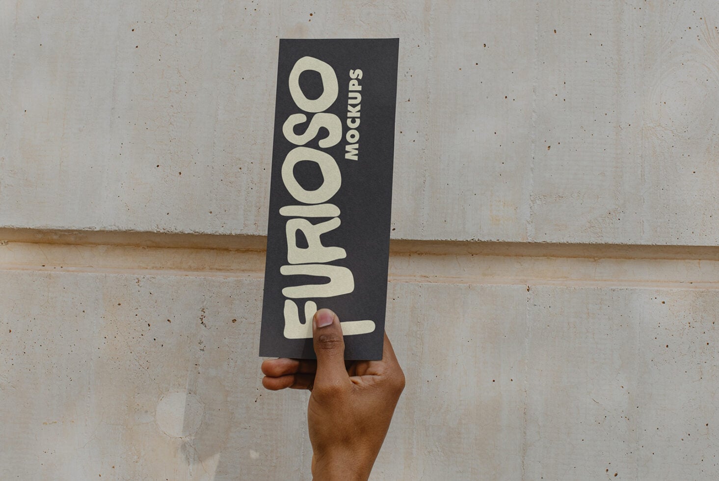 Dark charcoal business card held vertically with cream sans-serif text reading Furioso Mockups