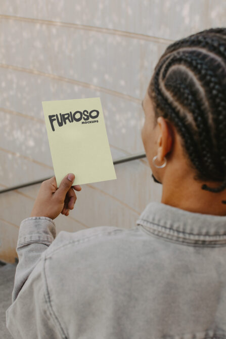 Cream colored card mockup in hand against textured white brick wall