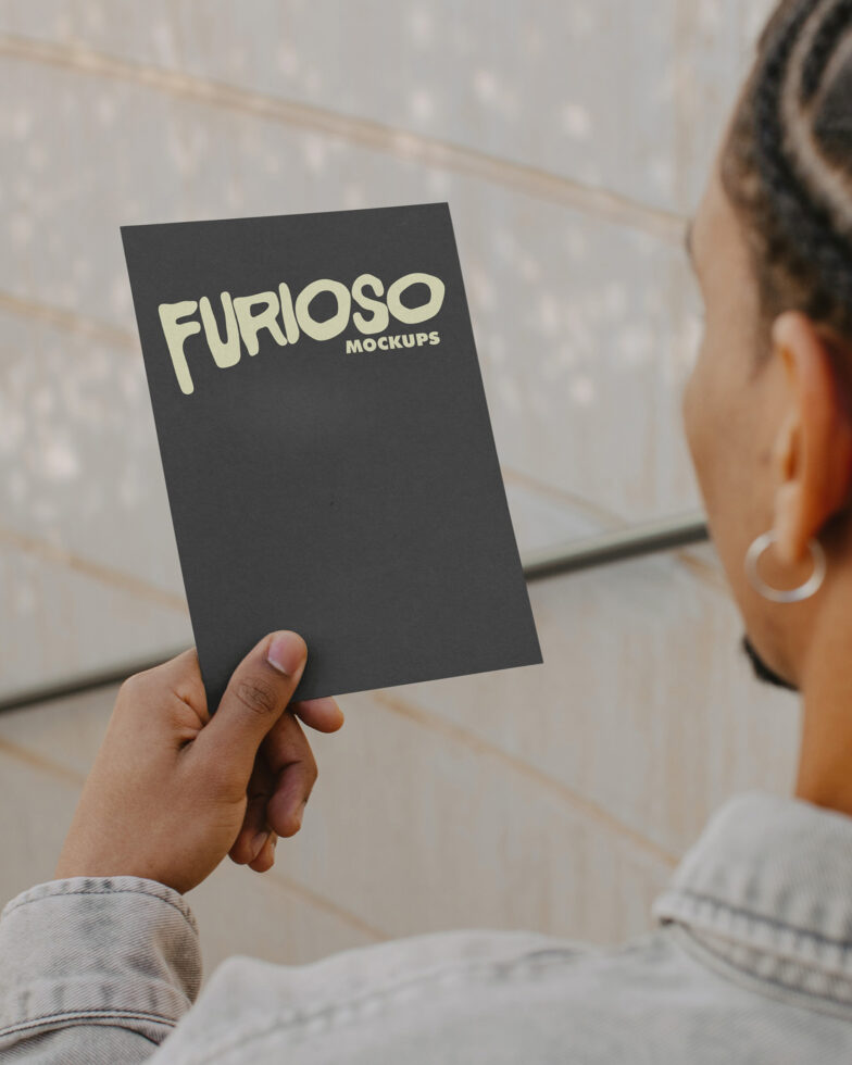 Dark charcoal card held in hand showing cream colored Furioso Mockups text