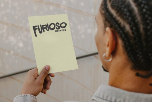 Light yellow card mockup held vertically against concrete backdrop