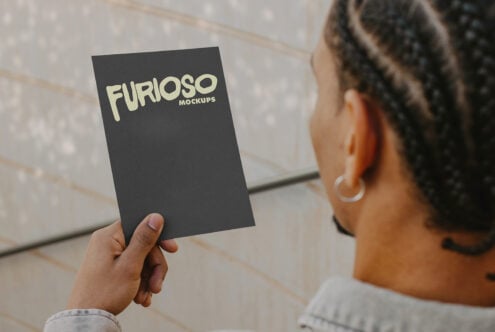 Dark card mockup being shown by person in casual gray jacket outdoors