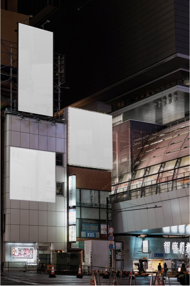 Two blank white billboards stacked on Tokyo building facade at night
