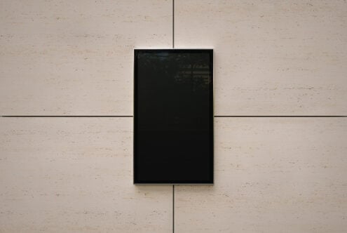 Empty black framed screen mounted on travertine wall with grid lines