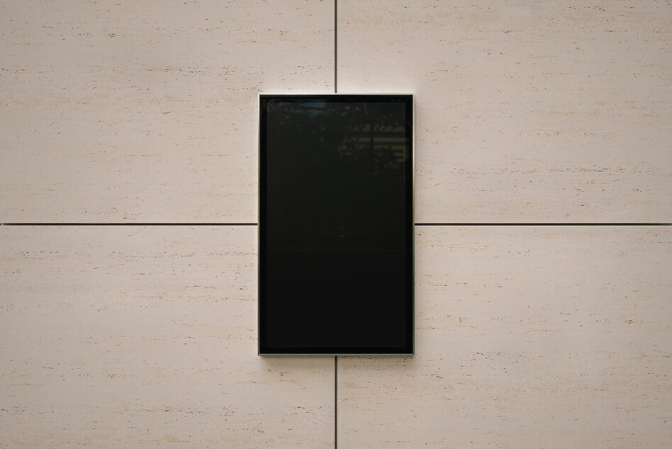 Empty black framed screen mounted on travertine wall with grid lines