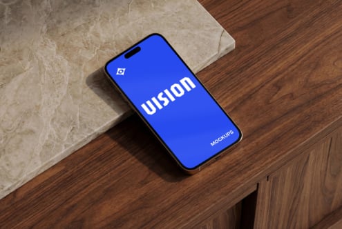 Smartphone on marble tile with bright blue screen displaying VISION text mockup