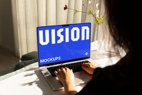 Person typing on laptop with black screen display in bright daylit workspace