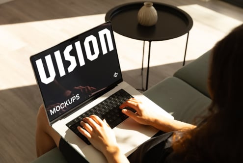 Laptop screen showing black background with white VISION text, hands typing on keyboard