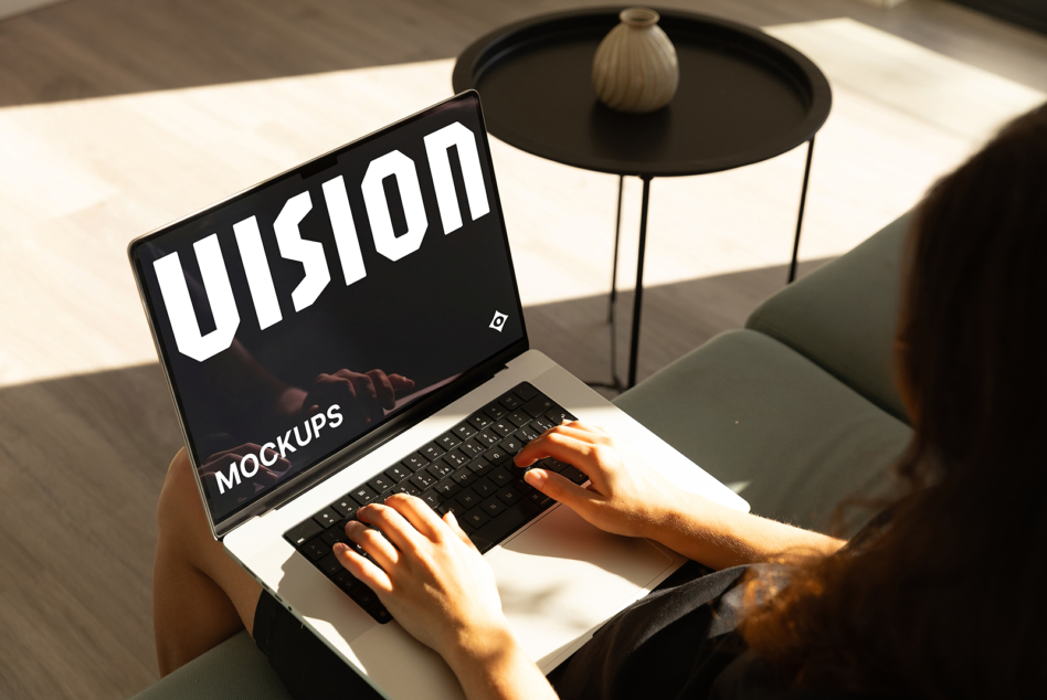 Laptop screen showing black background with white VISION text, hands typing on keyboard
