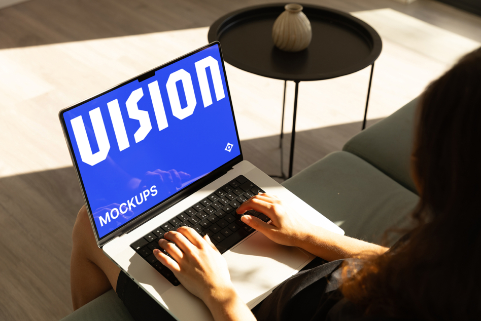 Laptop screen showing bright blue background with white VISION text, hands typing on keyboard