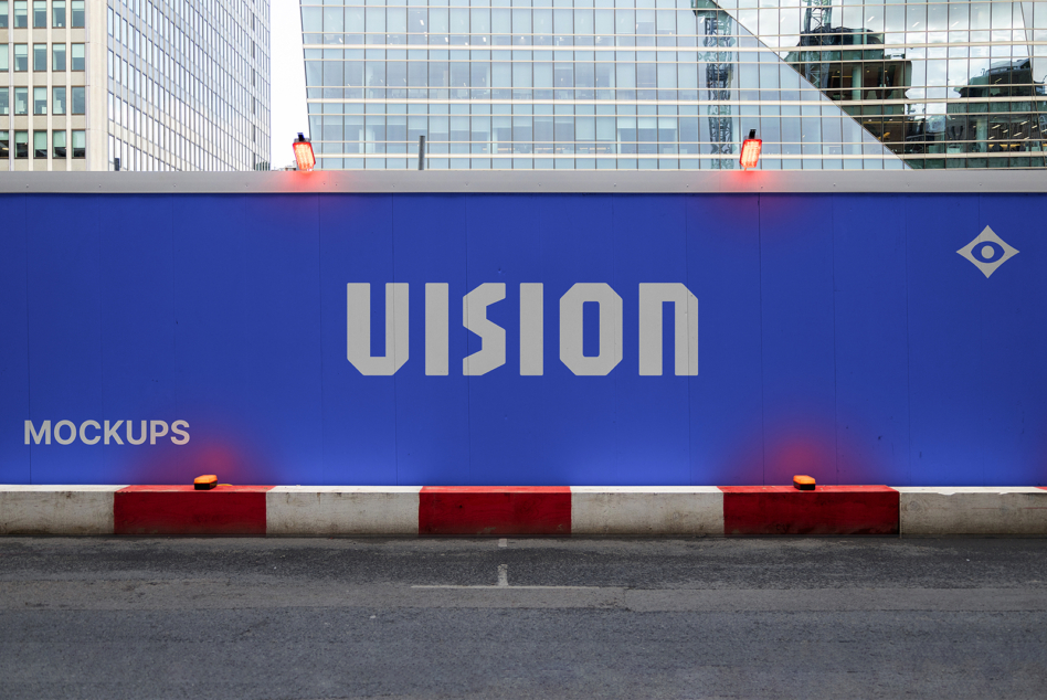 Blue construction hoarding displaying VISION branding with warning lights above