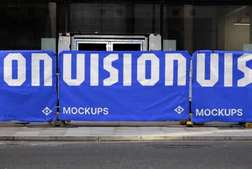 Multiple blue construction barriers with bold white typography on urban street
