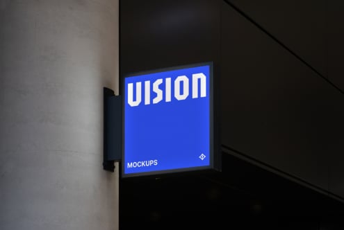 Bright blue illuminated storefront sign mounted on dark wall with white VISION text glowing