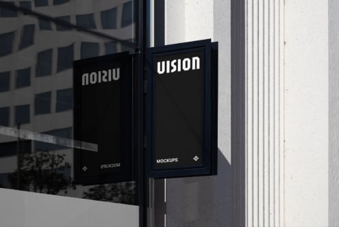 Dark storefront window with two black-framed signs showing white text mockup