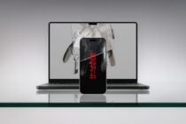 iPhone with red text displaying flower image in front of laptop
