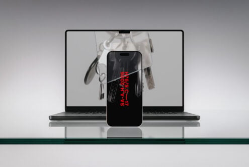 iPhone with red text displaying flower image in front of laptop