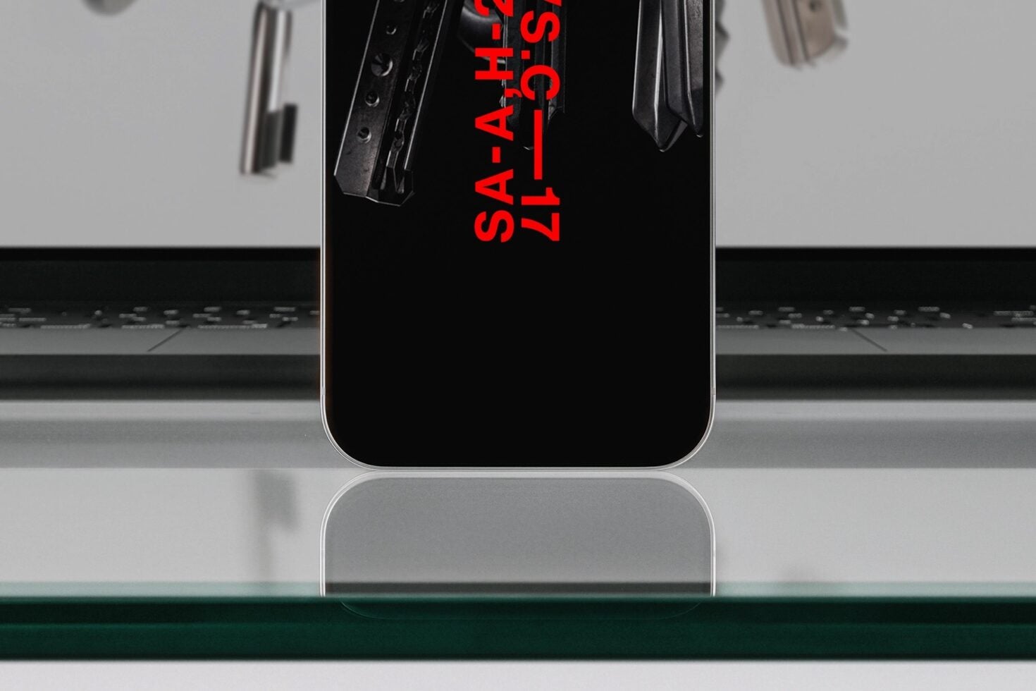 Phone standing on glass surface in front of laptop with red text