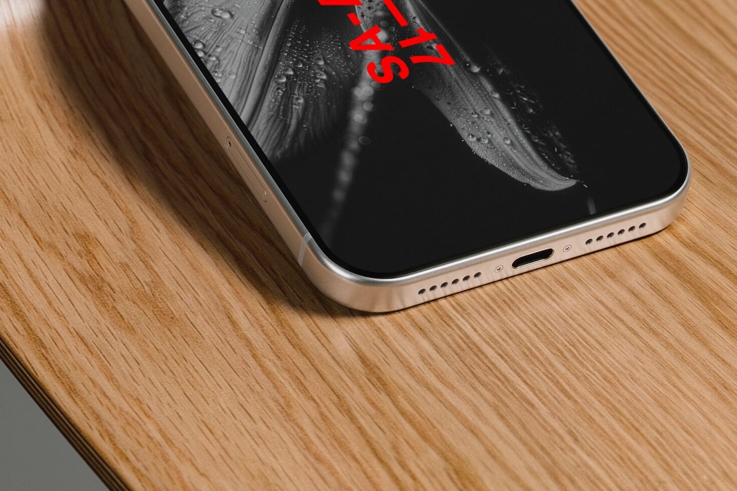 Gold iPhone with feather imagery on wood desk closeup