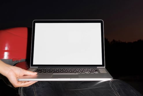 Laptop mockup with blank screen held in hands wearing red jacket against dark background
