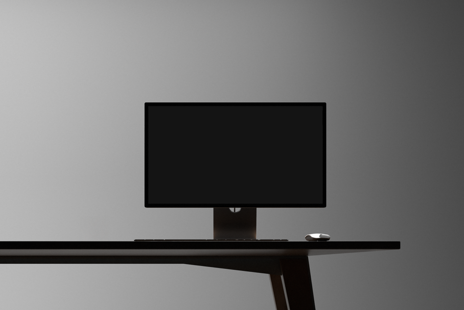 Minimalist desktop setup mockup featuring a blank screen monitor keyboard and mouse on a sleek black desk perfect for graphic designers and creatives