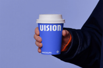 Person holding blue coffee cup with white VISION text on split colored background