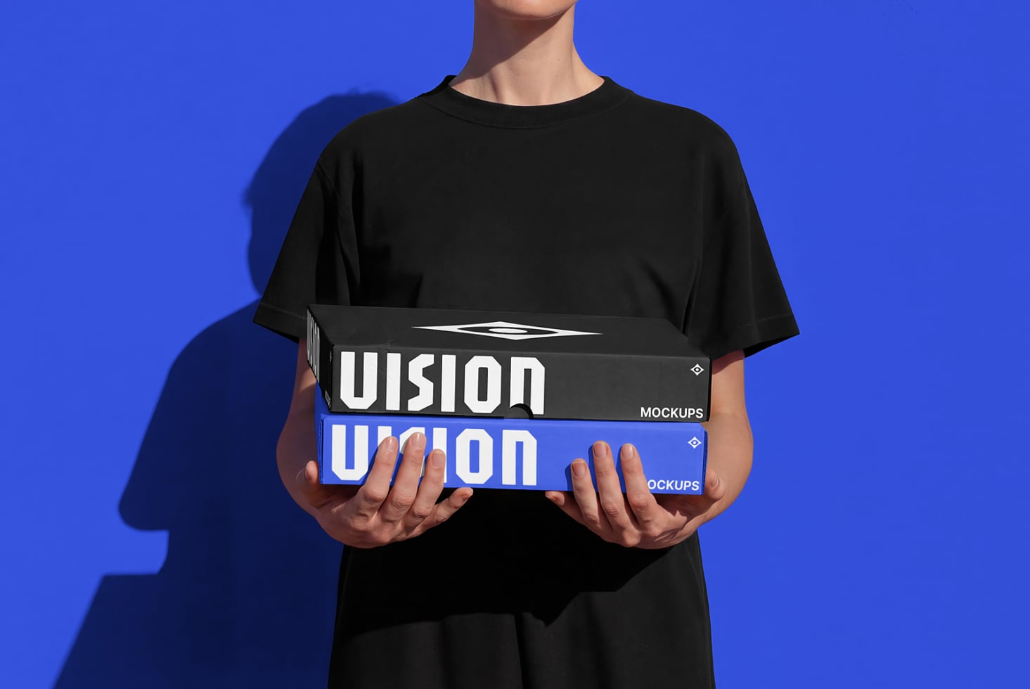 Person holding stacked box mockups with blue UIsion branding against blue background