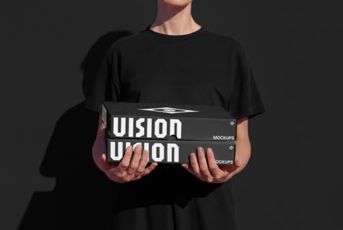 Person holding black box mockups with white UIsion branding stacked on dark background