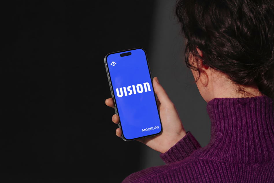 Woman in purple sweater holding iPhone 14 showing blue screen with VISION text