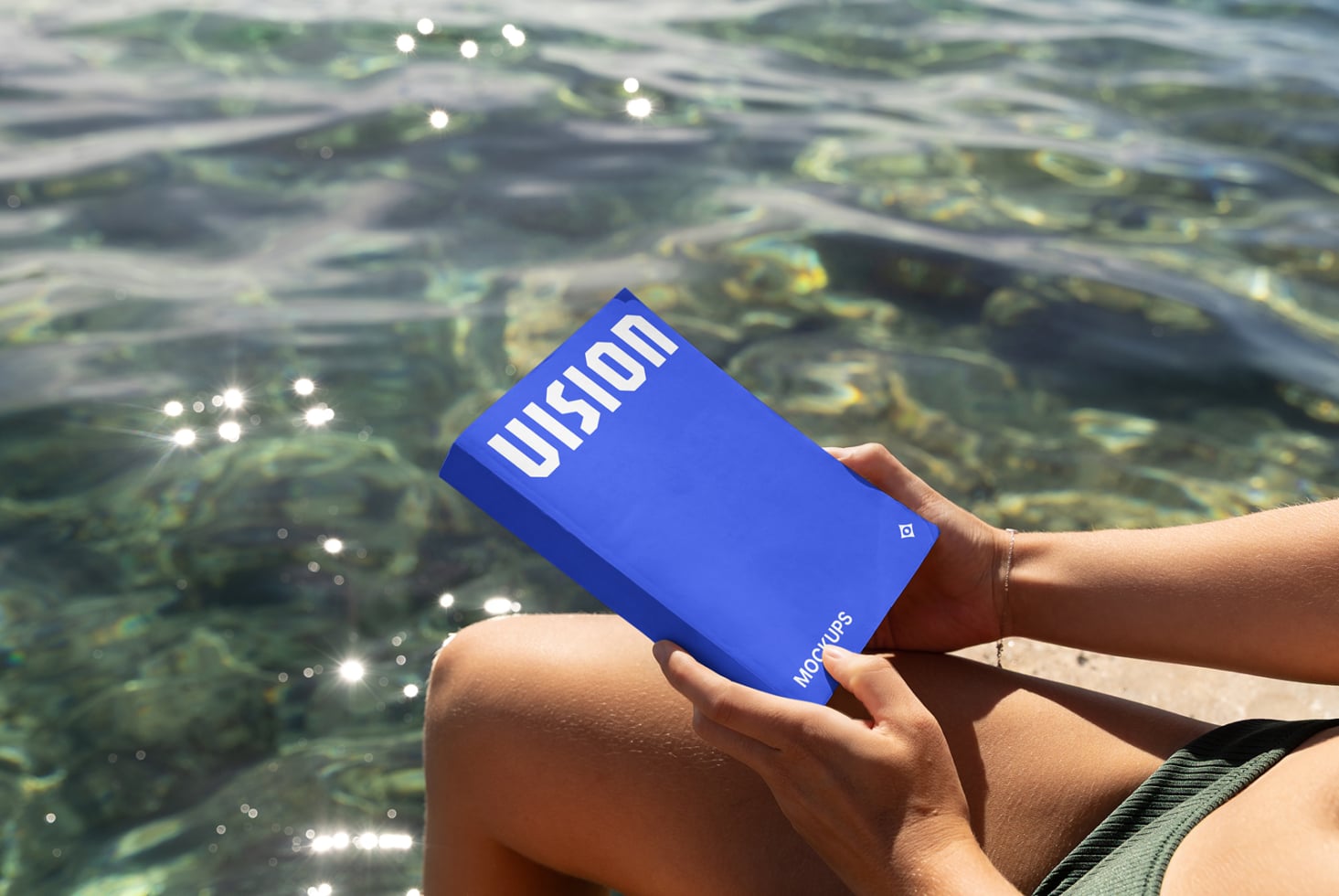 Bright blue box mockup held over sparkling ocean water with white VISION text visible