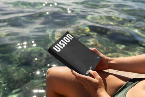 Black box mockup held over sparkling ocean water with white VISION text visible