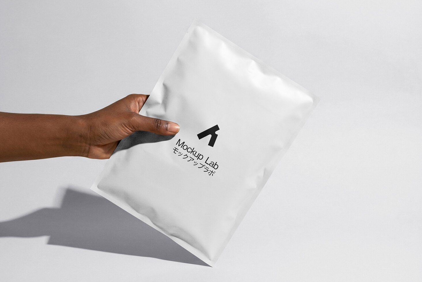 Hand holding white puffy envelope mockup with logo stamp