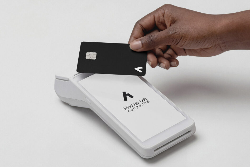 Hand swiping black credit card through white payment terminal reader device