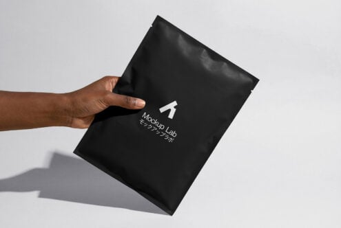 Hand tilting black envelope mockup showing creased texture