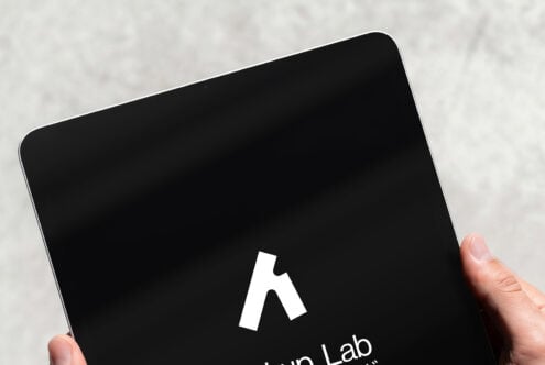 Hand holding tablet with black screen displaying white Mockup Lab logo