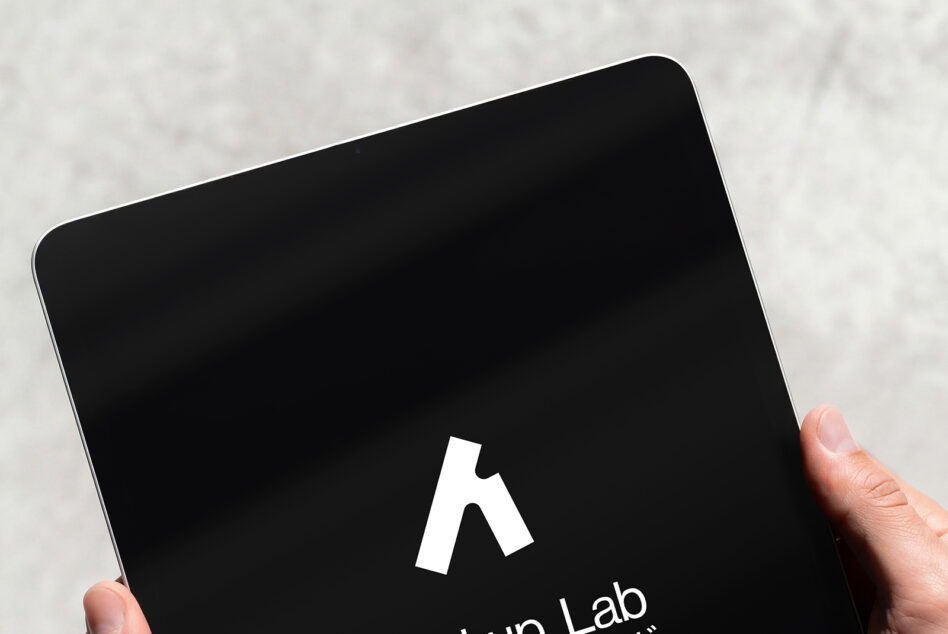 Hand holding tablet with black screen displaying white Mockup Lab logo