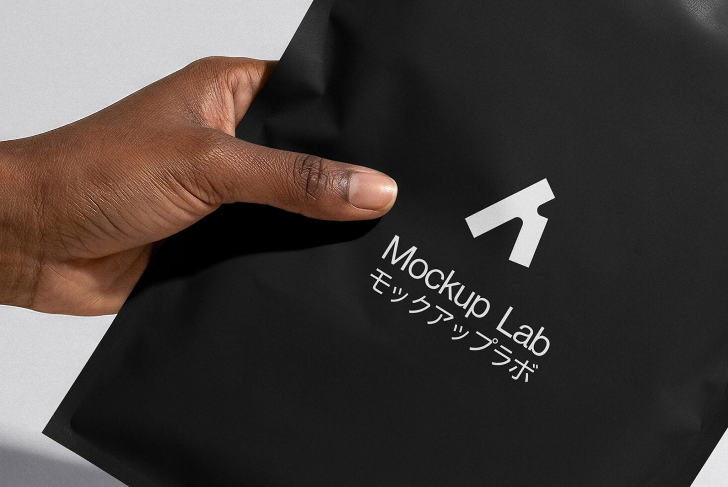 Hand holding black folded envelope with white logo print